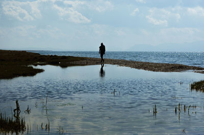 Man standing in sea against sky