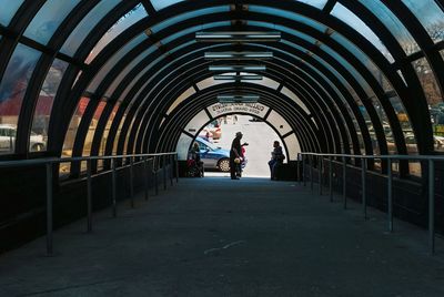 Rear view of people walking in tunnel