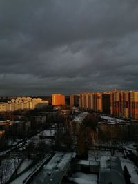 Buildings in city against storm clouds