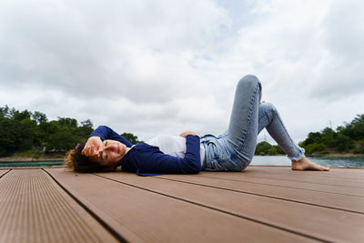 Woman lying on wood against sky