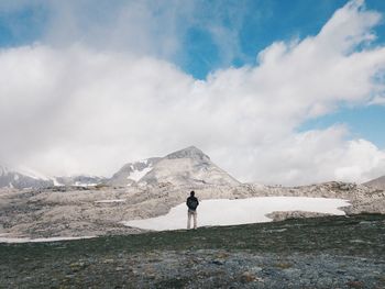 Woman standing on mountain against cloudy sky