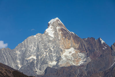 Low angle view of snowcapped mountain against blue sky