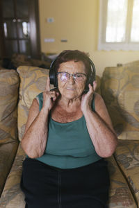 Happy senior woman enjoying to music through headphones at home