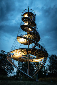 Low angle view of illuminated tower against cloudy sky