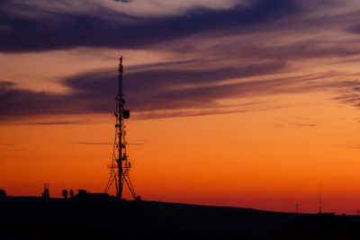 Silhouette of communications tower against sky during sunset