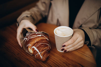 Midsection of woman holding coffee on table