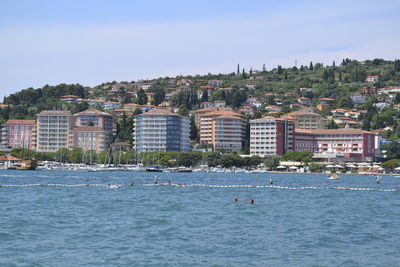 Buildings by sea against sky