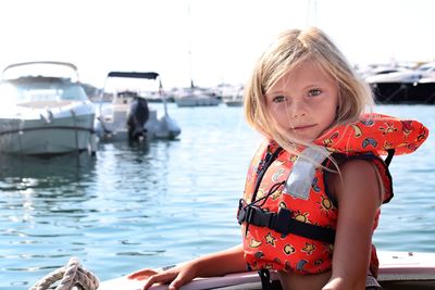 Portrait of girl wearing life jacket in boat on sea