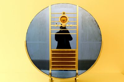 Woman standing by metallic built structure against wall