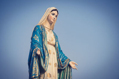 Low angle view of woman standing against clear blue sky