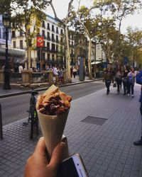 Close-up of woman holding ice cream cone on sidewalk