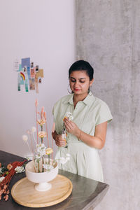 Woman of indian ethnicity of 30-34 years doing an ikebana centerpiece