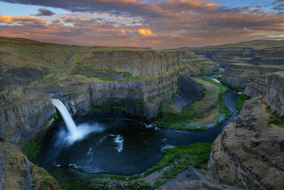 Scenic view of waterfall against sky during sunset