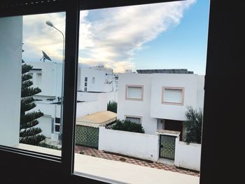 Buildings against sky seen through glass window