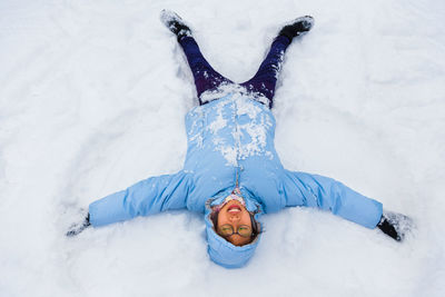 High angle view of girl lying down on snow