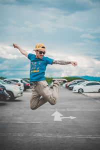 Full length of man jumping on road in city against sky