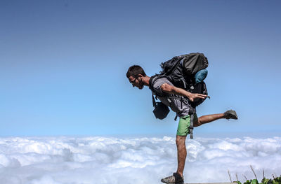 Hiker standing on cliff against cloudy sky