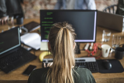 Blond female programmer coding over computer in startup company