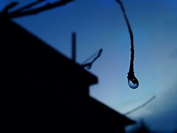 Close-up of silhouette water drop against sky