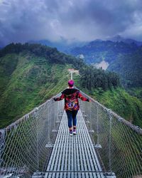 Rear view of woman walking on footbridge