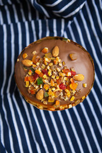 An easter cake decorated with candied fruits stands on a striped blue apron. 