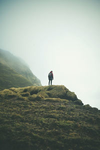 Man standing on rock against sky