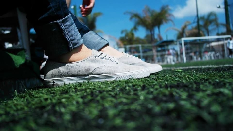 low section, lifestyles, grass, leisure activity, person, casual clothing, shoe, sitting, standing, relaxation, park - man made space, focus on foreground, selective focus, field, men, day, outdoors