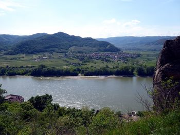 Scenic view of river by mountains against sky