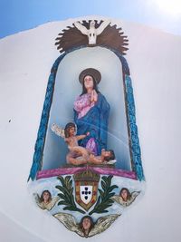 Woman sitting on cross against wall