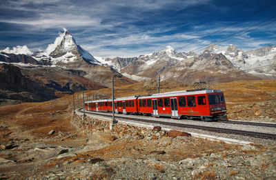 Train on railroad track against cloudy sky