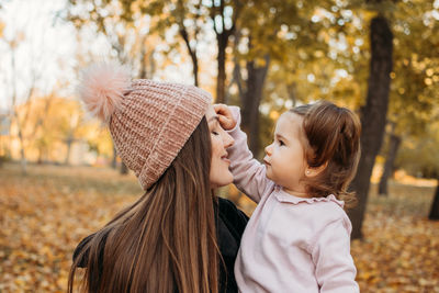 Ways to carry a toddler. close up outdoors portrait of happy family mom and toddler baby girl in