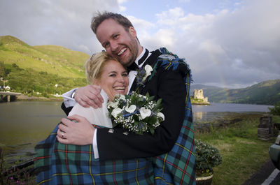 Portrait of smiling couple embracing against lake