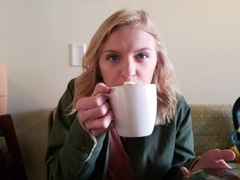 Portrait of young woman drinking coffee at home