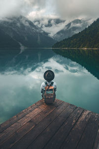 Man on pier over lake against sky