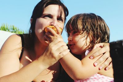 Close-up of girl feeding mother on sunny day