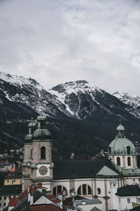 Houses and snowcapped mountains against sky