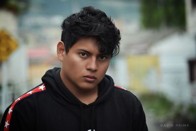 Portrait of serious young man wearing black hooded shirt in city