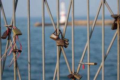 Close-up of rusty padlocks on railing against seascape