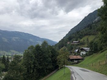 Road amidst trees and buildings against sky