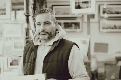 Mature man standing against picture frames