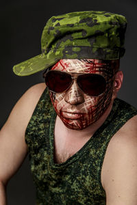 Portrait of man with face paint wearing sunglasses and cap