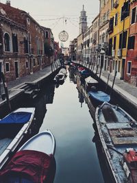 Boats moored on canal amidst buildings