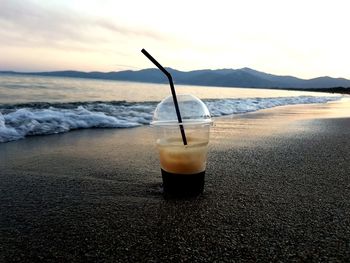 Close-up of drink on beach against sky