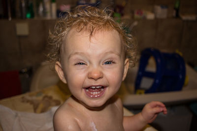 Portrait of shirtless cute baby laughing while sitting at home