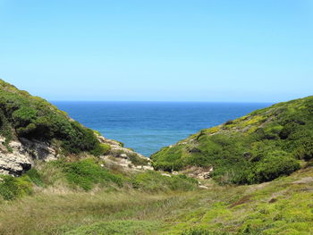 Scenic view of sea and mountains against clear blue sky