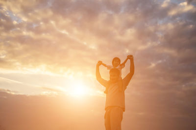 Rear view of silhouette man standing against sky during sunset