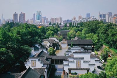 Trees and buildings in city against sky