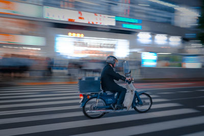 Side view of man riding bicycle on road in city