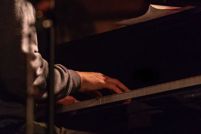 Midsection of man playing piano at night