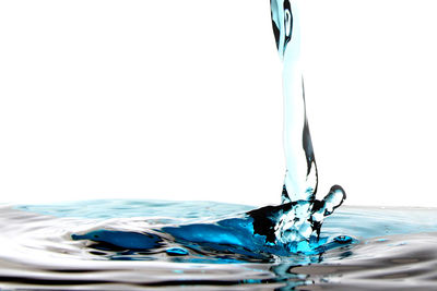 Close-up of water splashing on glass against white background